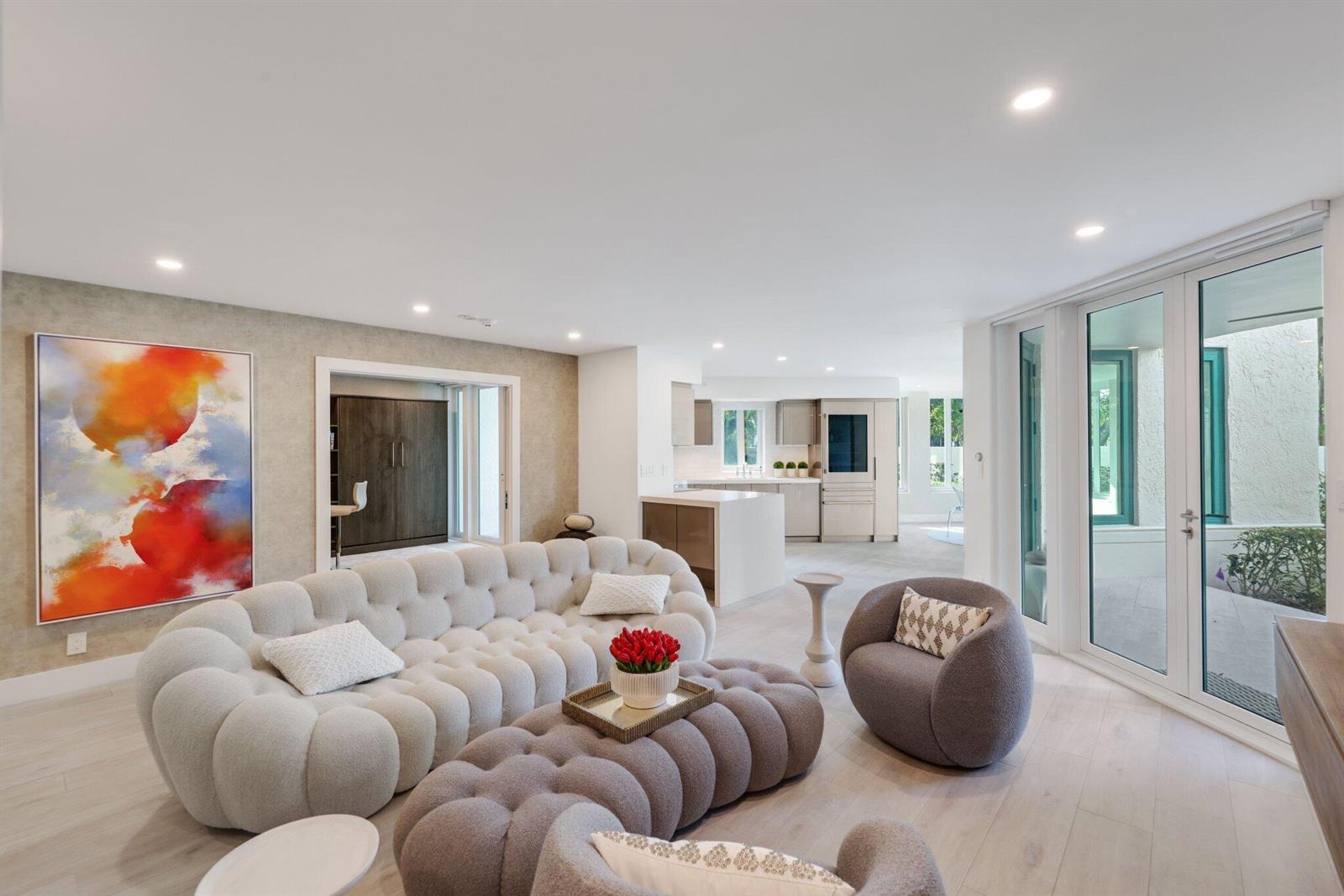 A modern living room features a tufted sofa, matching ottoman, and an open-concept kitchen — 100 SE 5th Avenue # 106, Boca Raton FL 33432, BOCA RATON, FL