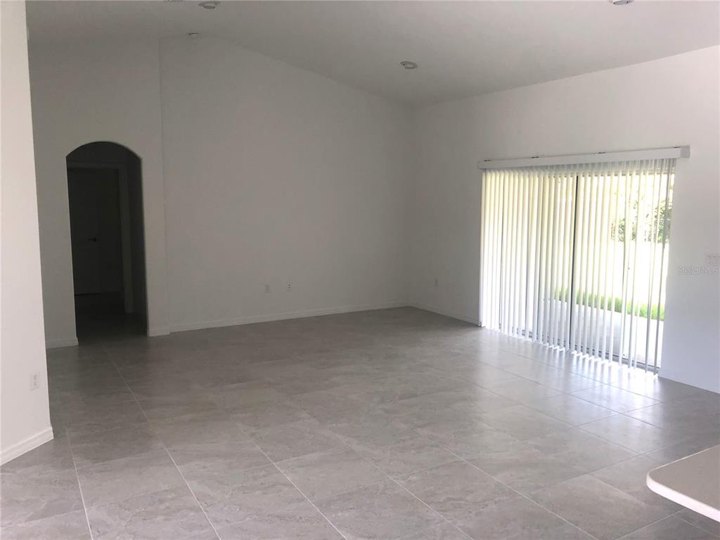 An empty room features light gray tile flooring, white walls, and a sliding glass door — 10 FLINTHILL LANE, PALM COAST, FL