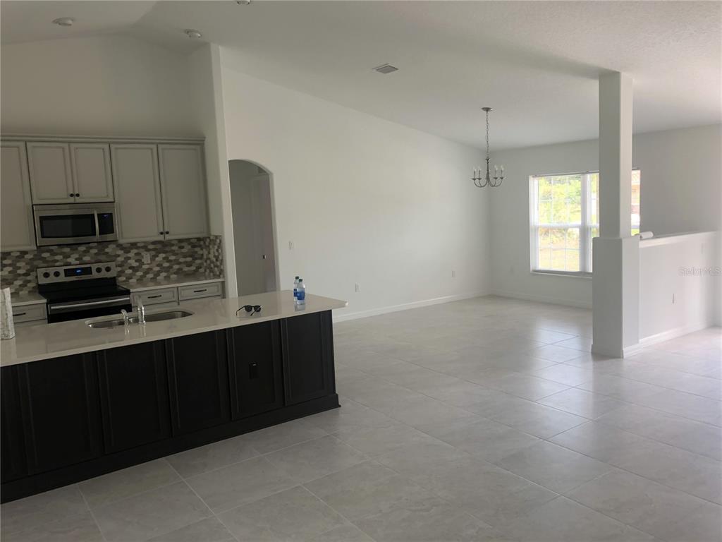 A kitchen with a dark island and light cabinets opens into a spacious living area — 10 FLINTHILL LANE, PALM COAST, FL