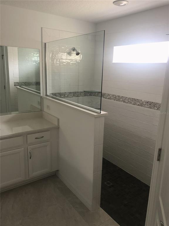 A bathroom features a white vanity, a glass-enclosed walk-in shower, and white subway tile walls — 10 FLINTHILL LANE, PALM COAST, FL