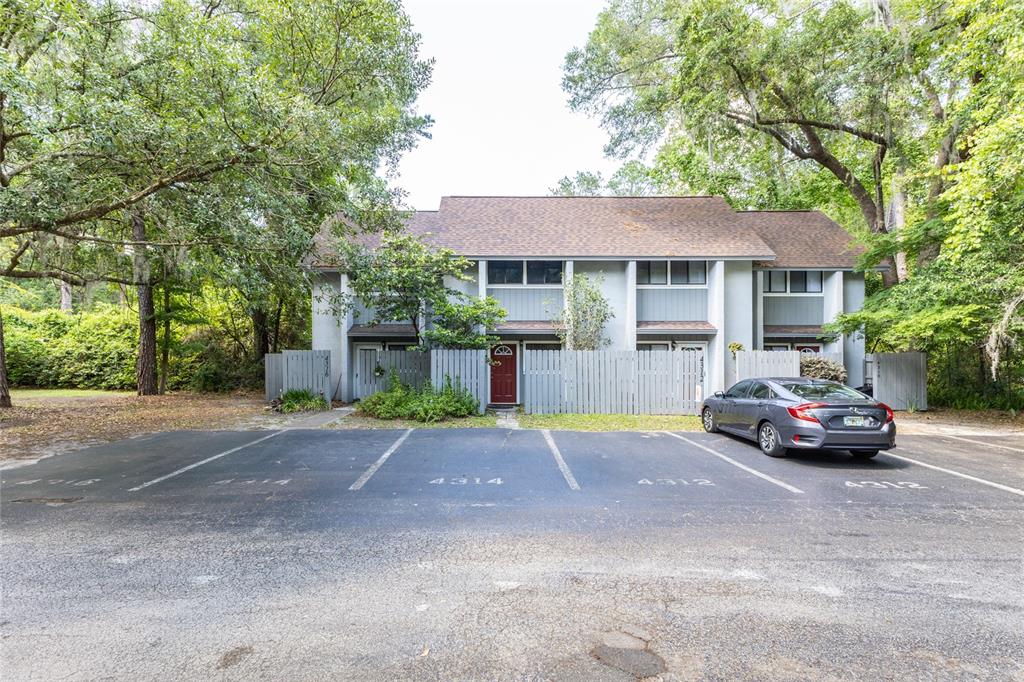 A two-story townhouse with a red front door and a gray car parked in front — 4314 NW 41ST LANE UNIT 73, GAINESVILLE, FL