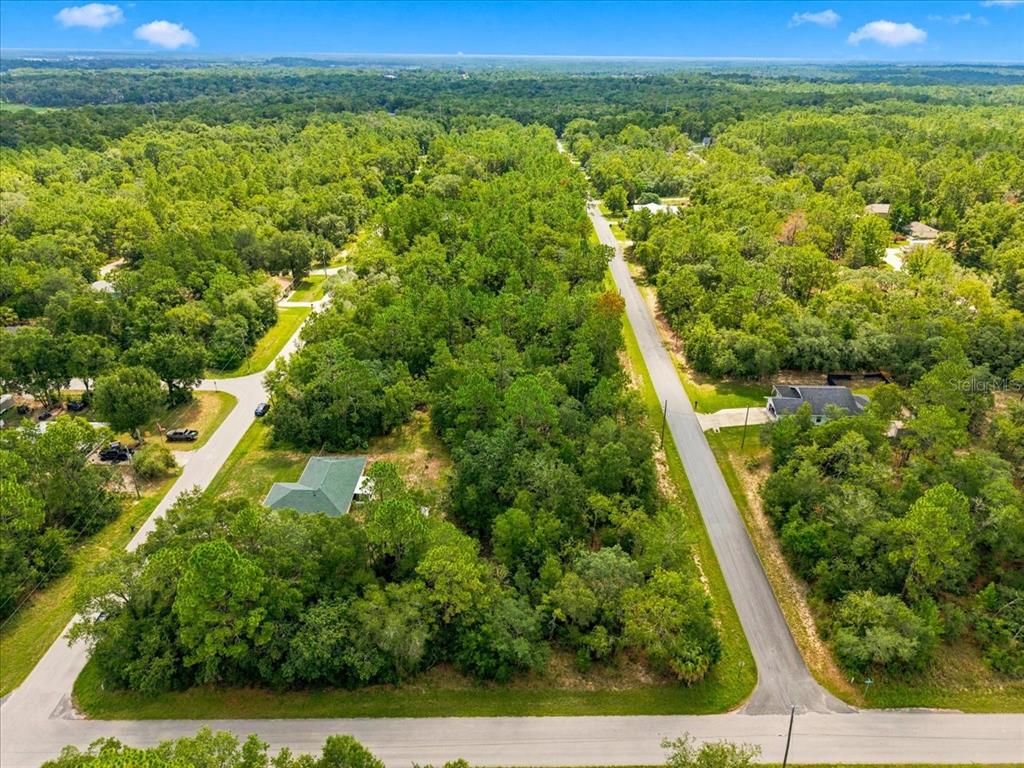 An aerial view shows a wooded residential lot situated between two paved roads — 3015 E MAY STREET, INVERNESS, FL