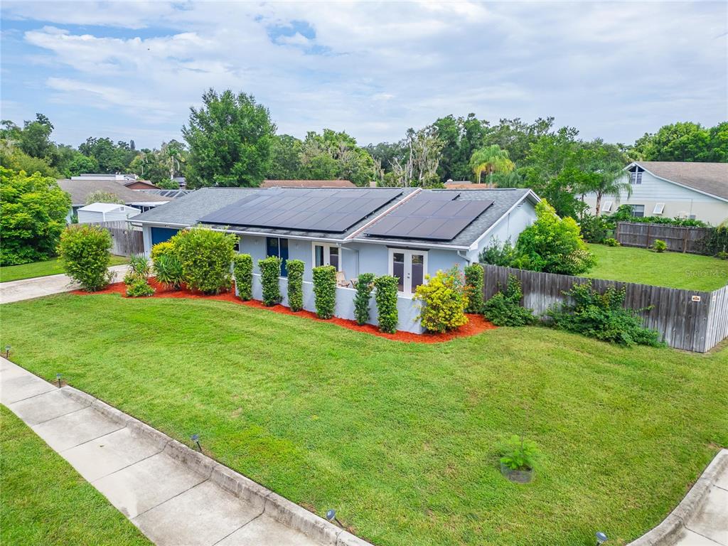 A light blue single-story house features a solar panel array on its roof and landscaping — 1120 LAKEMONT DRIVE, VALRICO, FL