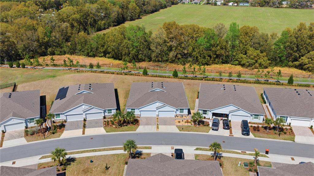 An aerial view shows several suburban townhomes with gray roofs and driveways near a field — 5369 NW 48TH PLACE, OCALA, FL