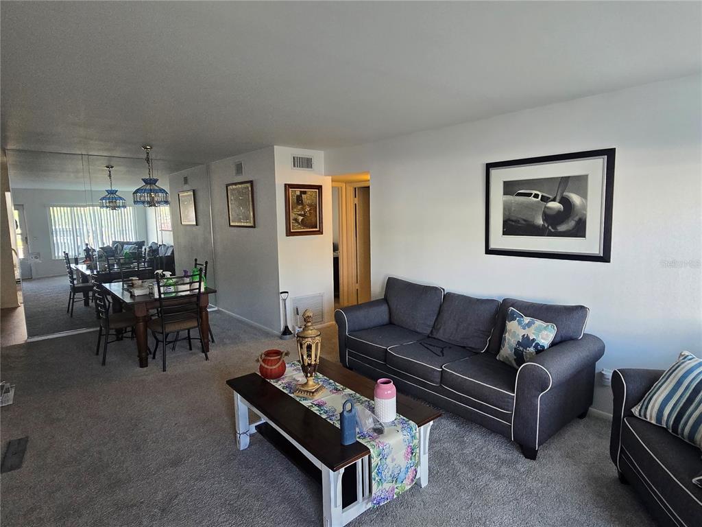 A living room with gray sofas, a coffee table, and an adjacent dining area — 2428 COLUMBIA DRIVE UNIT 22, CLEARWATER, FL