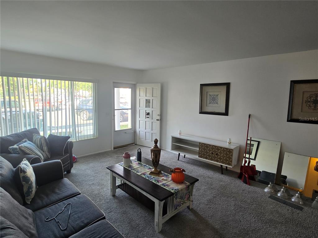 A living room features gray carpet, a dark sofa, a coffee table, and a white console — 2428 COLUMBIA DRIVE UNIT 22, CLEARWATER, FL