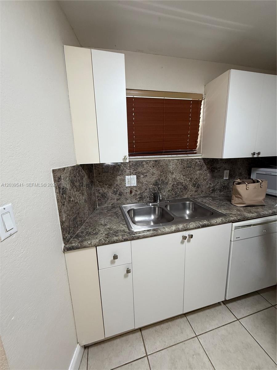 A kitchen features white cabinets, a dark marble-patterned countertop, and a double-basin stainless steel sink — 4205 N UNIVERSITY DR # 309, Sunrise FL 33351, SUNRISE, FL