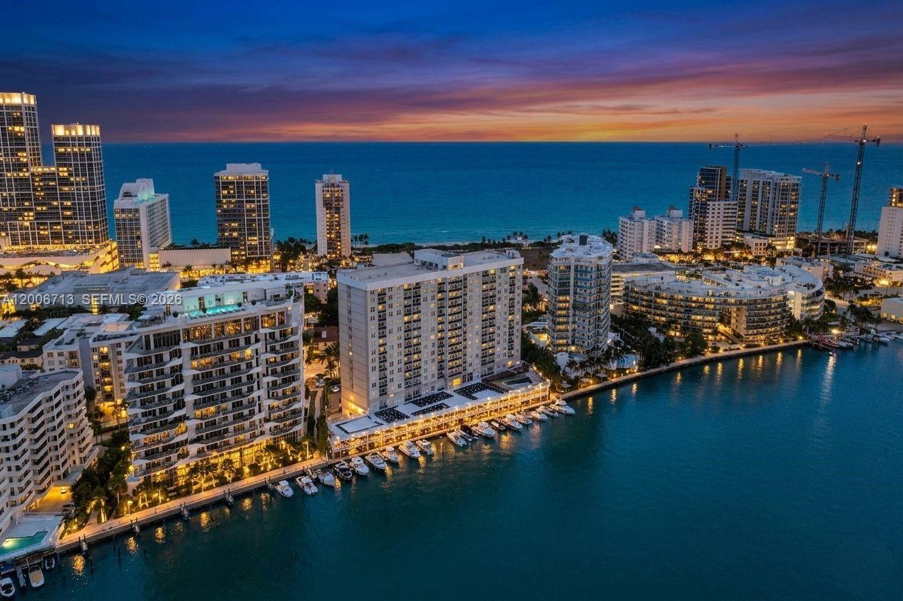 A balcony with a glass railing overlooks a city skyline and ocean at sunset — 6770 Indian Creek Dr # 14C, Miami Beach FL 33141, MIAMI BEACH, FL