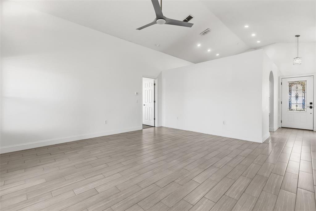 An empty living room features white walls, light wood-look tile flooring, and a ceiling fan — 1746 WESTMINSTER TRAIL, CLERMONT, FL