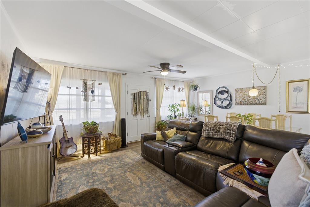 A living room features a brown leather sectional, a patterned area rug, and a television — 872 LAKE SHORE TERRACE, INTERLACHEN, FL