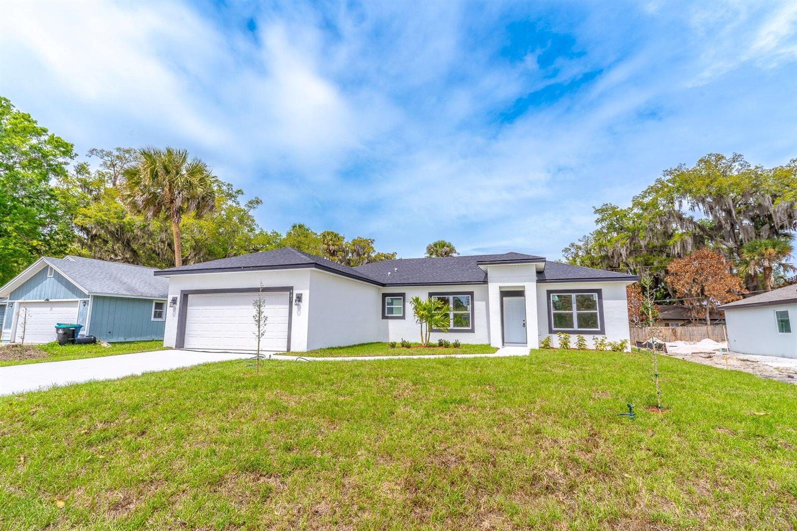 A single-story white house with a dark roof, garage, and front yard — 983 NW Pace Dr Drive NW, Palm Bay FL 32907, PALM BAY, FL