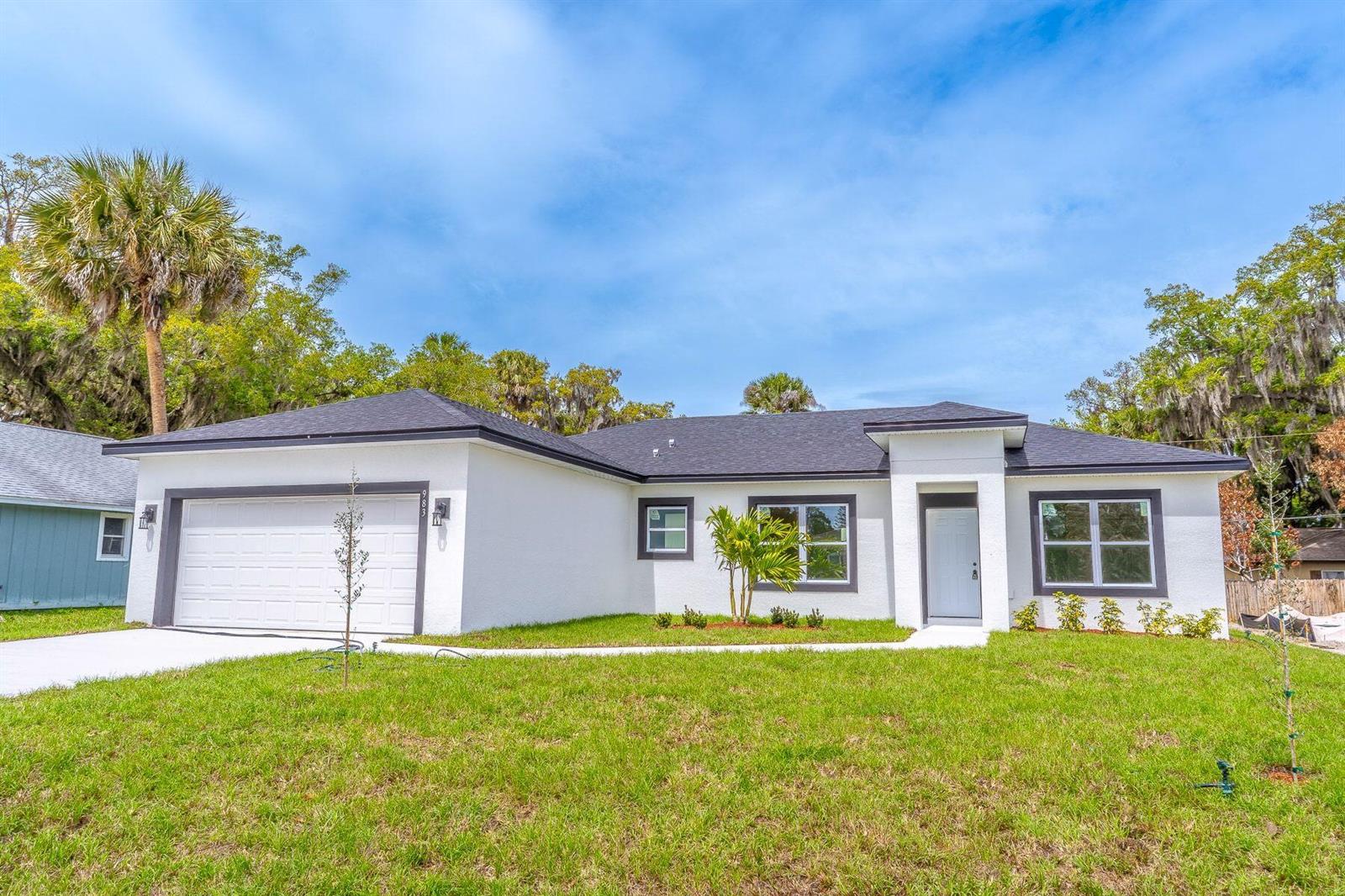 A single-story white house with a dark roof, a two-car garage, and a front entrance — 983 NW Pace Dr Drive NW, Palm Bay FL 32907, PALM BAY, FL