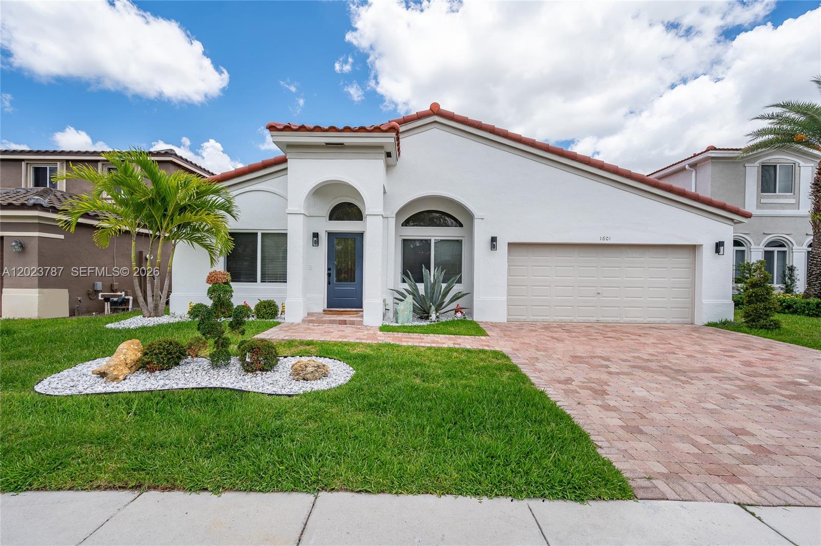 A single-story house with a white stucco exterior, red tile roof, and a paved driveway — 1601 SW 106th Ter, Davie FL 33324, DAVIE, FL