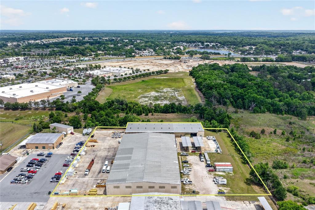 An aerial view shows a large industrial warehouse building surrounded by parking and wooded land — 722 DUCK LAKE ROAD, LADY LAKE, FL