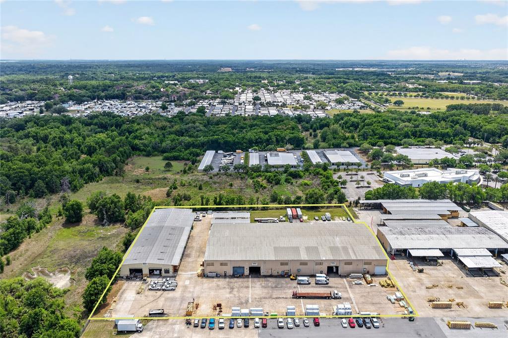 An aerial view shows two industrial warehouse buildings with surrounding parking lots and storage areas — 722 DUCK LAKE ROAD, LADY LAKE, FL