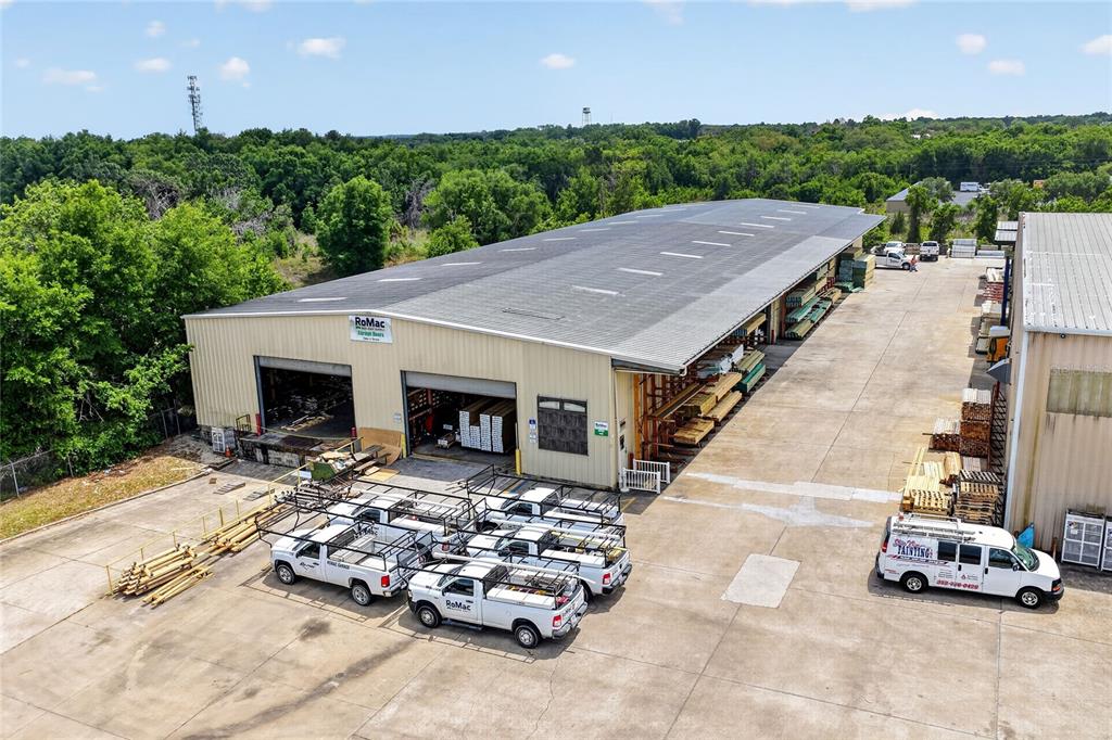 An aerial view shows a large industrial warehouse building with several work trucks parked outside — 722 DUCK LAKE ROAD, LADY LAKE, FL
