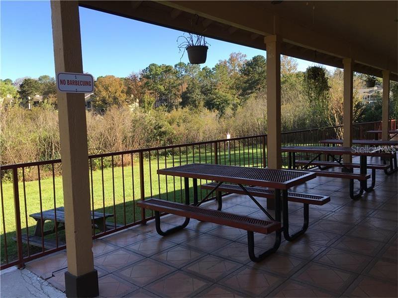 A covered outdoor patio features metal picnic tables, a tiled floor, and a metal railing — 625 DORY LANE UNIT 303, ALTAMONTE SPRINGS, FL