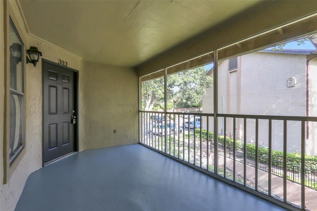 A covered, screened-in balcony features a dark gray entry door labeled 303 and painted flooring — 625 DORY LANE UNIT 303, ALTAMONTE SPRINGS, FL