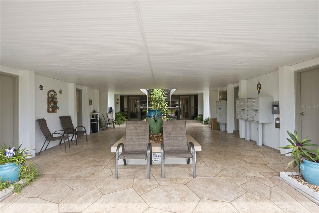 A covered outdoor patio features stone-patterned flooring, seating areas, and a central planter — 21300 BRINSON AVENUE UNIT 201, PORT CHARLOTTE, FL