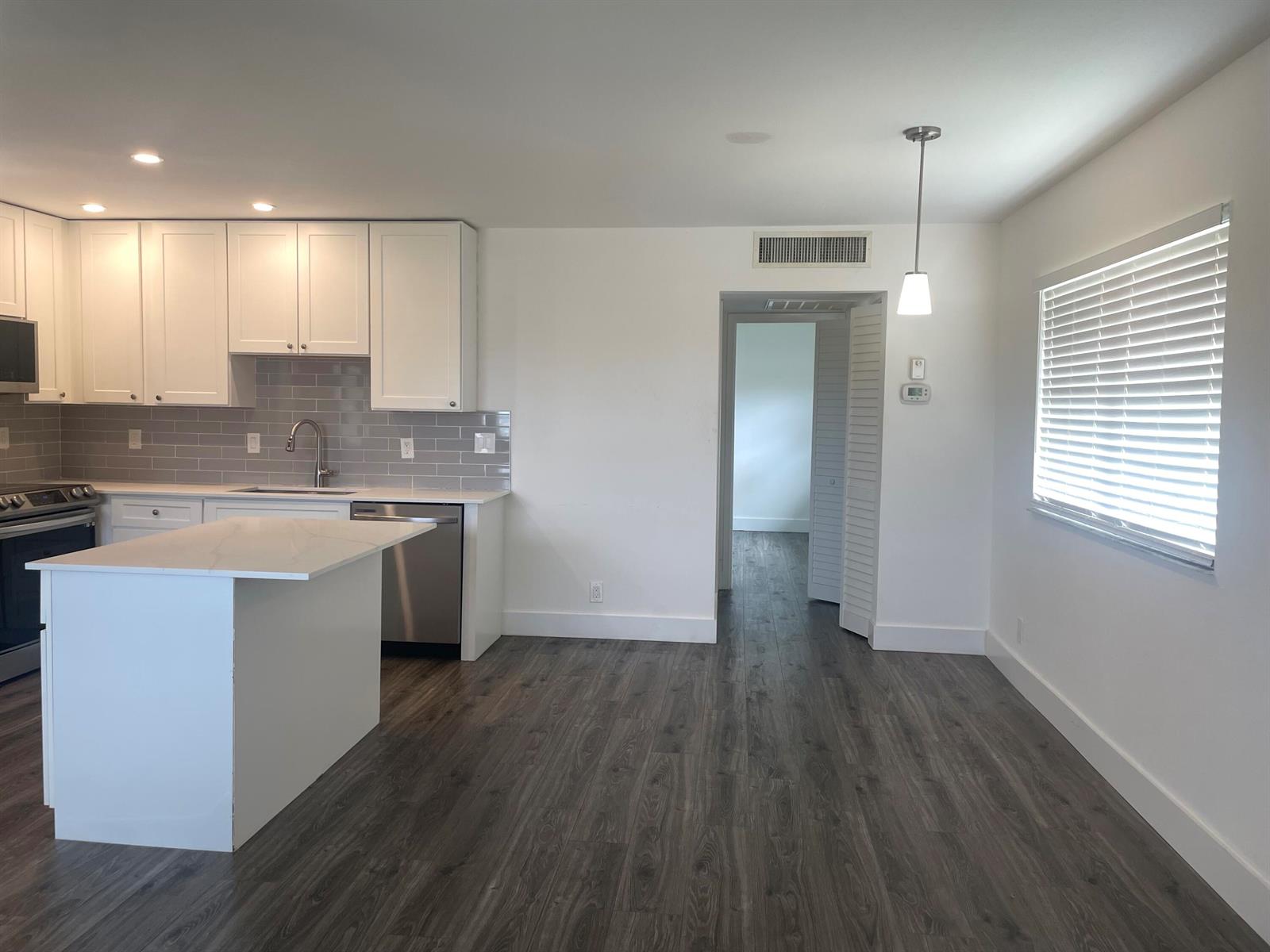 A kitchen with white cabinets, stainless steel appliances, and a central island on wood flooring — 650 N Brittany N # 650, Delray Beach FL 33446, DELRAY BEACH, FL
