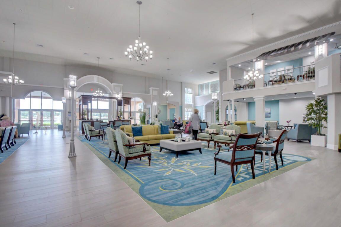 A spacious lobby features a large blue patterned rug, seating areas, and multiple chandeliers — 650 N Brittany N # 650, Delray Beach FL 33446, DELRAY BEACH, FL