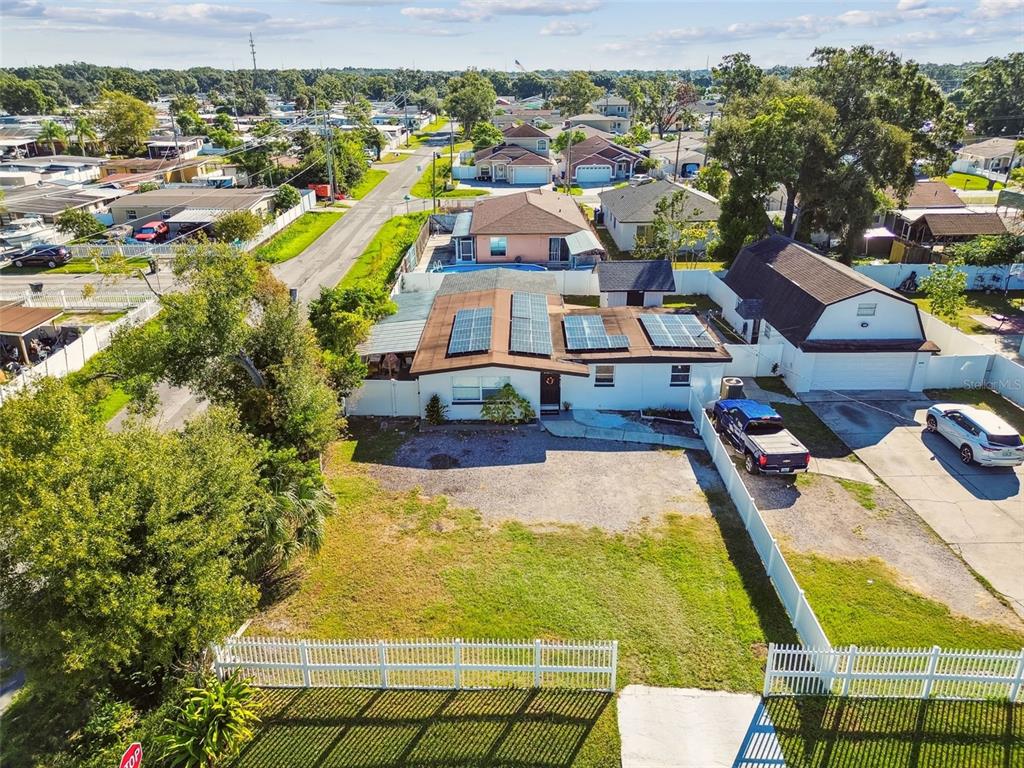An aerial view shows a single-story house with solar panels and a large front yard — 5825 N THATCHER AVENUE, TAMPA, FL