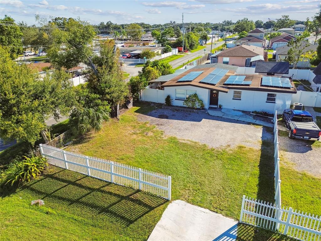 An aerial view shows a house with solar panels, a gravel driveway, and white fencing — 5825 N THATCHER AVENUE, TAMPA, FL