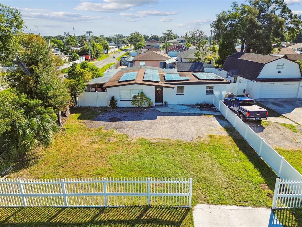 An aerial view of a single-story house with solar panels and a large front yard — 5825 N THATCHER AVENUE, TAMPA, FL