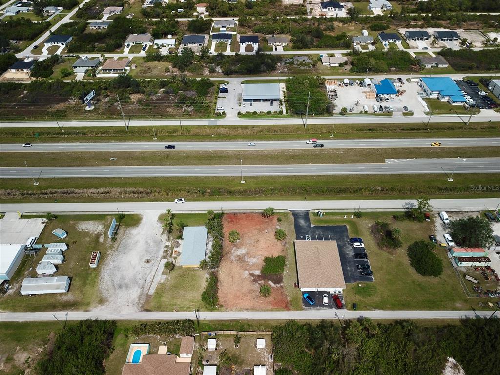 An aerial view shows a vacant lot situated between two commercial buildings near a highway — 4303 & 4307 S ACCESS ROAD, ENGLEWOOD, FL