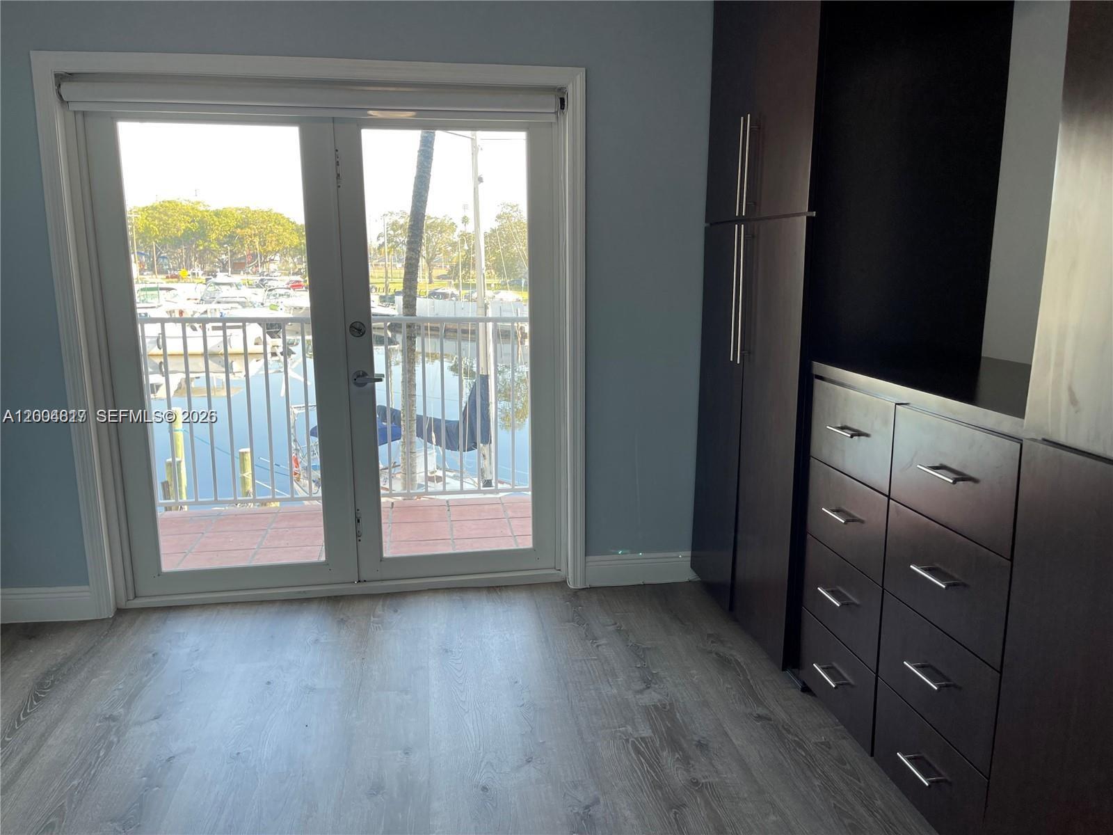 A room with gray wood-look flooring, dark cabinetry, and double doors opening to a marina — 2415 NW 16th St Rd # 102, Miami FL 33125, MIAMI, FL