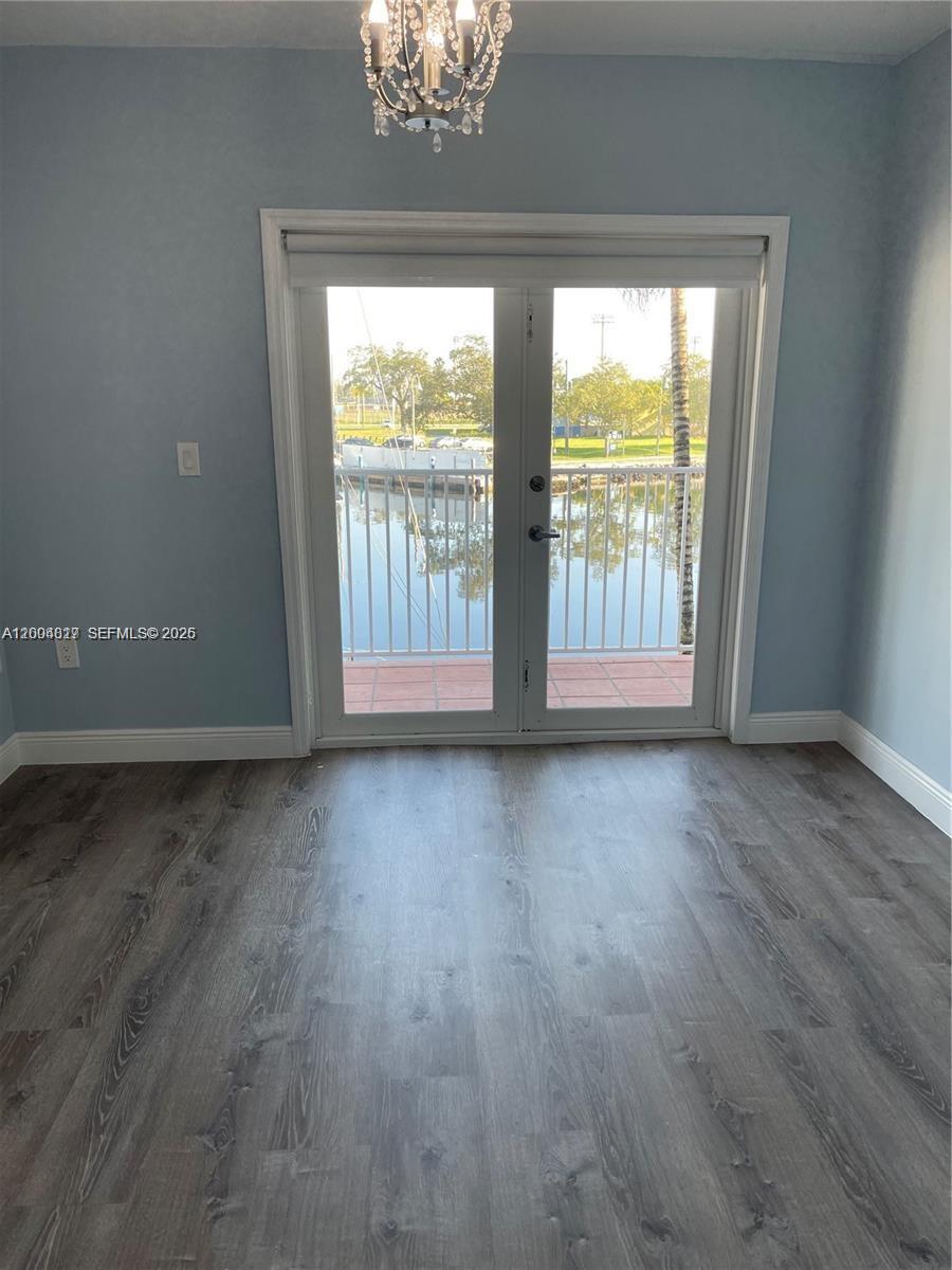 A room with light blue walls, wood-look flooring, a chandelier, and glass doors overlooking water — 2415 NW 16th St Rd # 102, Miami FL 33125, MIAMI, FL