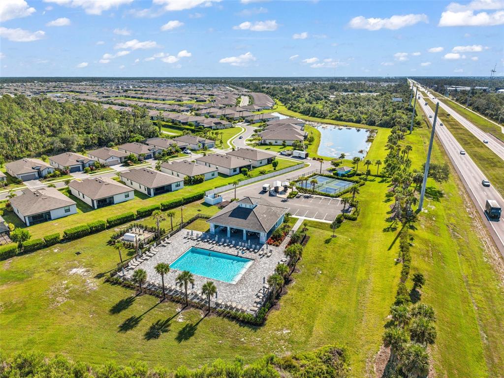 An aerial view shows a community pool, clubhouse, tennis courts, and nearby residential homes — 2017 MACKEREL STREET, PORT CHARLOTTE, FL