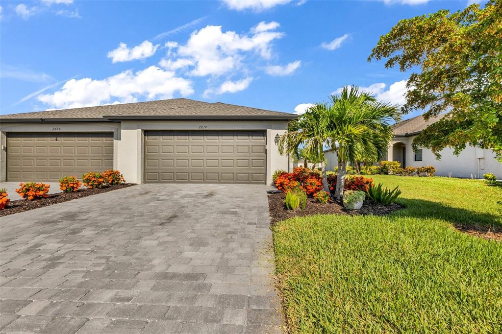 A paved driveway leads to the two-car garage of a single-story suburban home — 2017 MACKEREL STREET, PORT CHARLOTTE, FL