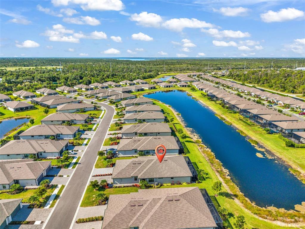 An aerial view shows a residential neighborhood with houses surrounding a long, narrow lake — 2017 MACKEREL STREET, PORT CHARLOTTE, FL