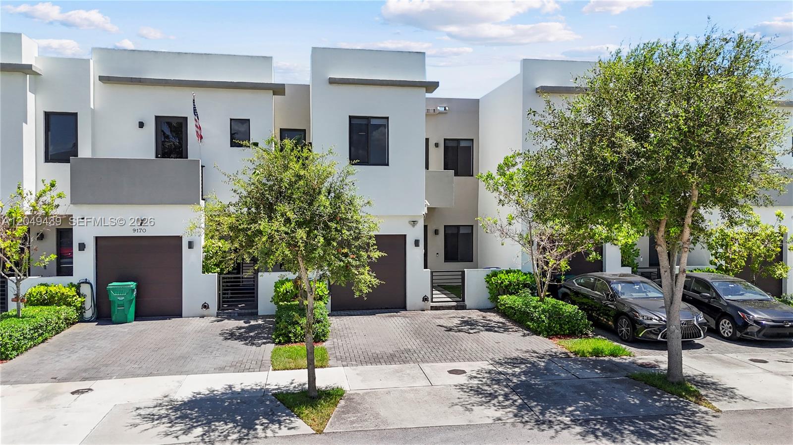 A row of modern two-story townhouses features white stucco facades, brown garage doors, and paved driveways — 9174 SW 5th Ln, Miami FL 33174, MIAMI, FL