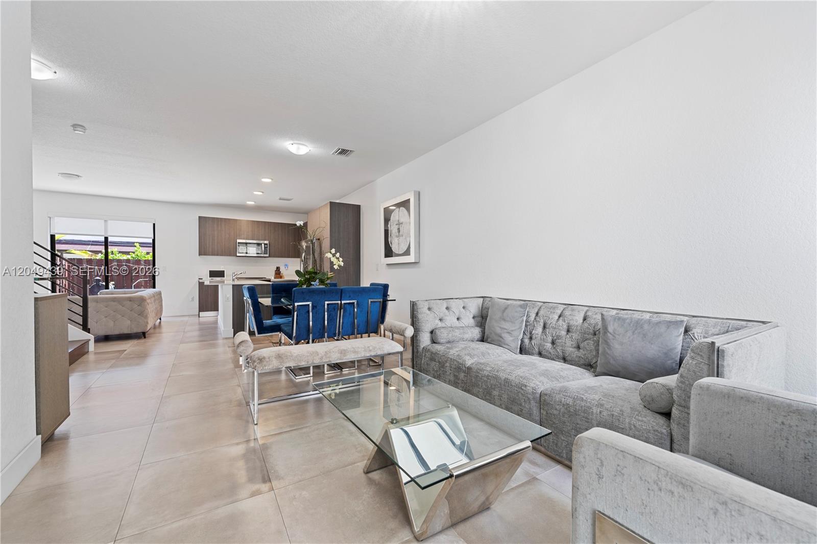 A modern open-concept living and dining area features tile flooring and contemporary gray furniture — 9174 SW 5th Ln, Miami FL 33174, MIAMI, FL