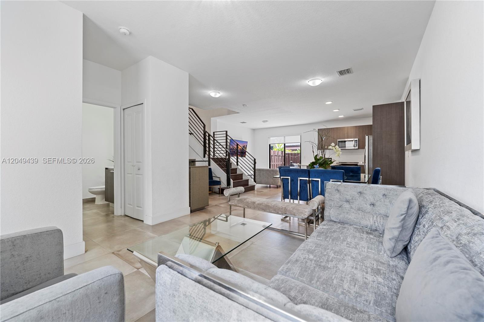 A living room and dining area feature tile floors, a staircase, and modern furniture — 9174 SW 5th Ln, Miami FL 33174, MIAMI, FL