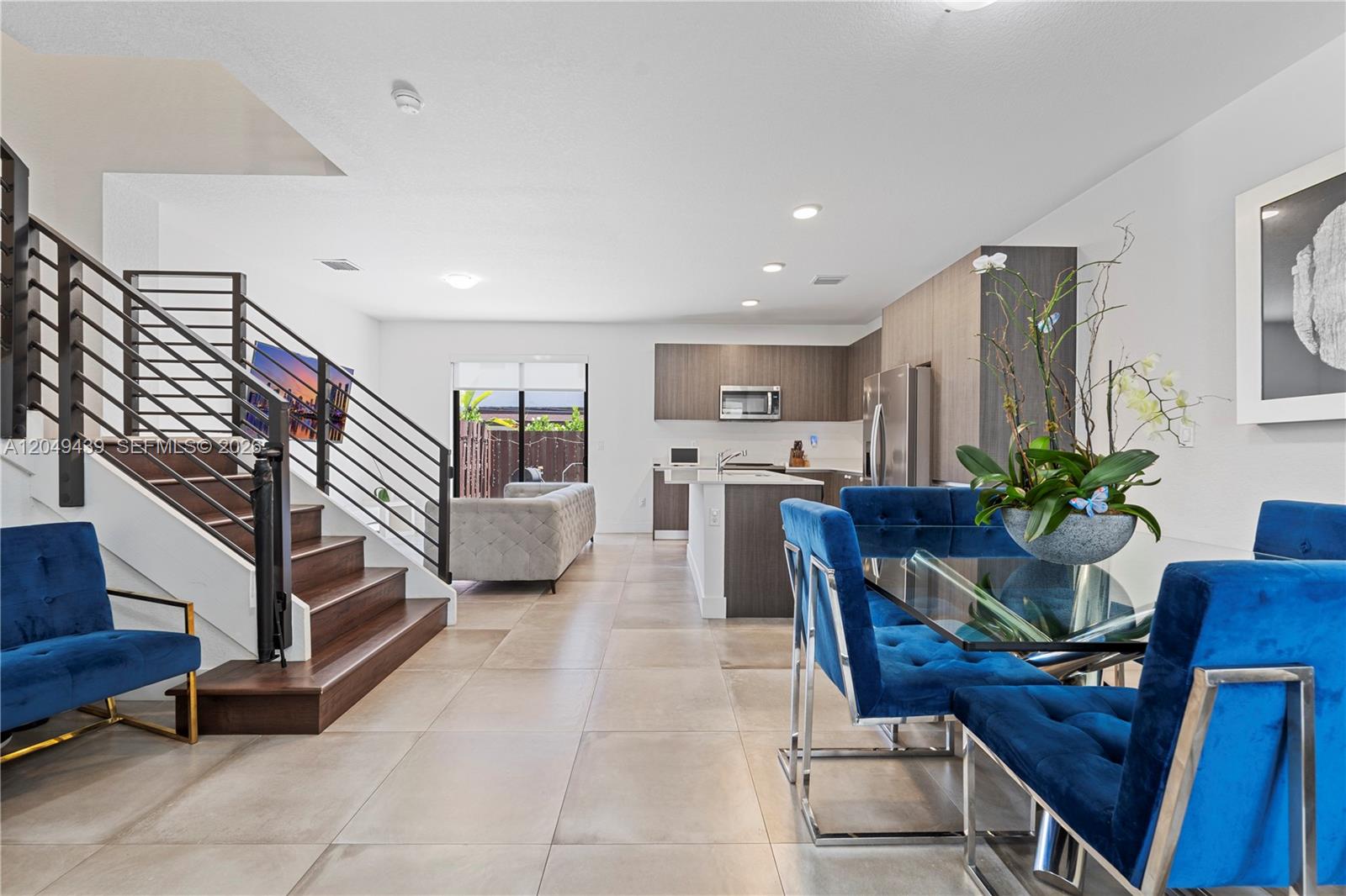 An open-concept living area features a modern kitchen, a staircase with metal railings, and dining furniture — 9174 SW 5th Ln, Miami FL 33174, MIAMI, FL