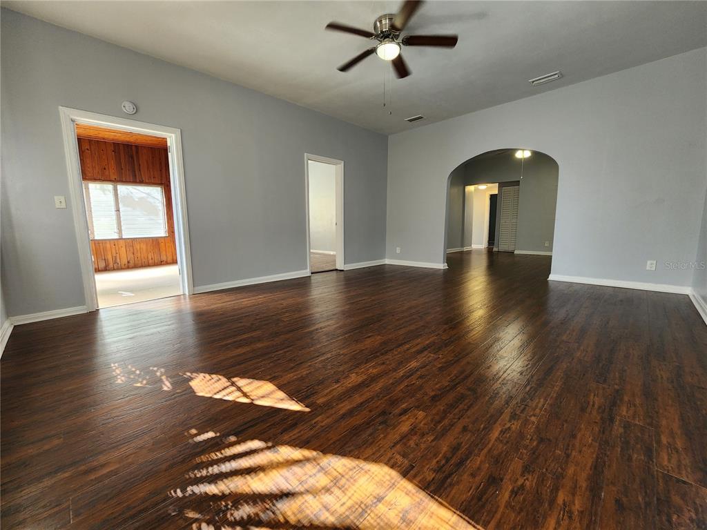 A spacious living room features dark wood-look flooring, light gray walls, and a ceiling fan — 1238 CLEVELAND STREET, JACKSONVILLE, FL