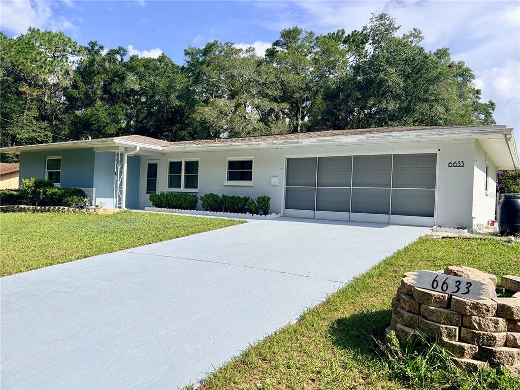 A single-story house with a light blue exterior, a driveway, and a stone mailbox — 6633 E GURLEY STREET, INVERNESS, FL