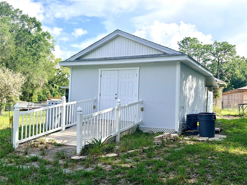 A light gray detached shed with a white ramp and double doors in a yard — 6633 E GURLEY STREET, INVERNESS, FL