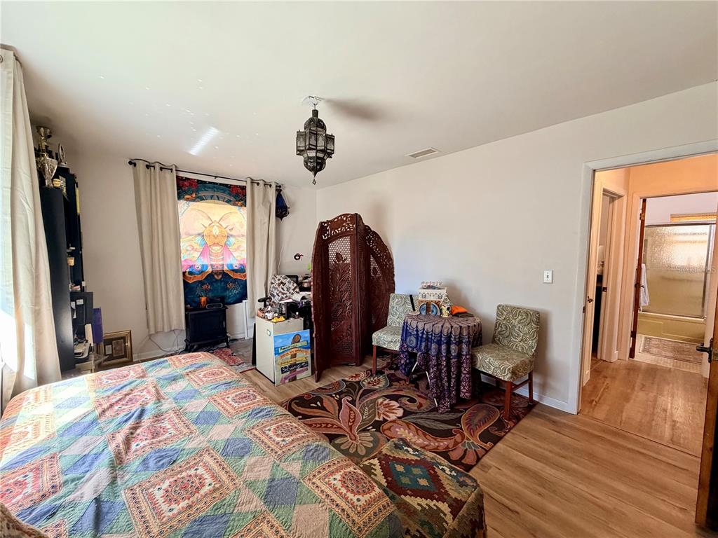 A bedroom features a patterned quilt, a small table with two chairs, and a folding screen — 6633 E GURLEY STREET, INVERNESS, FL