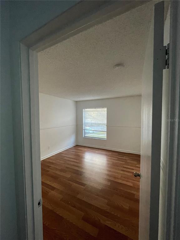 An empty room with wood-look flooring, white walls, and a single window — 5444 E MICHIGAN STREET UNIT 5444-6, ORLANDO, FL