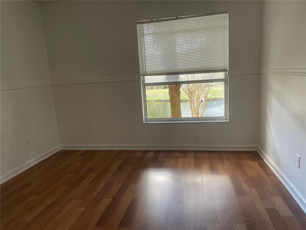 An empty room features wood-look flooring, white walls with chair rail molding, and a window — 5444 E MICHIGAN STREET UNIT 5444-6, ORLANDO, FL
