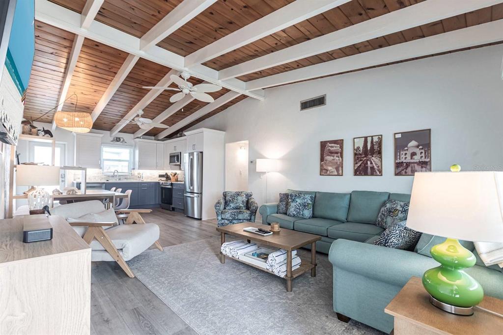 A living room with a wood-plank vaulted ceiling, blue sofa, and an open kitchen — 6006 MIDNIGHT PASS ROAD UNIT 44, SARASOTA, FL