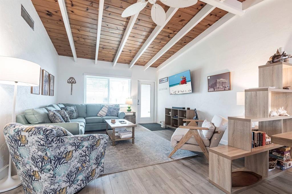 A living room features a vaulted wood-plank ceiling, a sectional sofa, and a patterned armchair — 6006 MIDNIGHT PASS ROAD UNIT 44, SARASOTA, FL