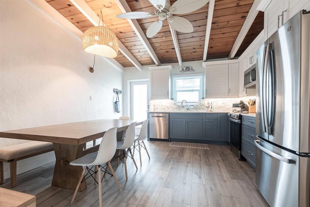 A kitchen and dining area with wood-plank ceilings, white walls, and gray lower cabinets — 6006 MIDNIGHT PASS ROAD UNIT 44, SARASOTA, FL