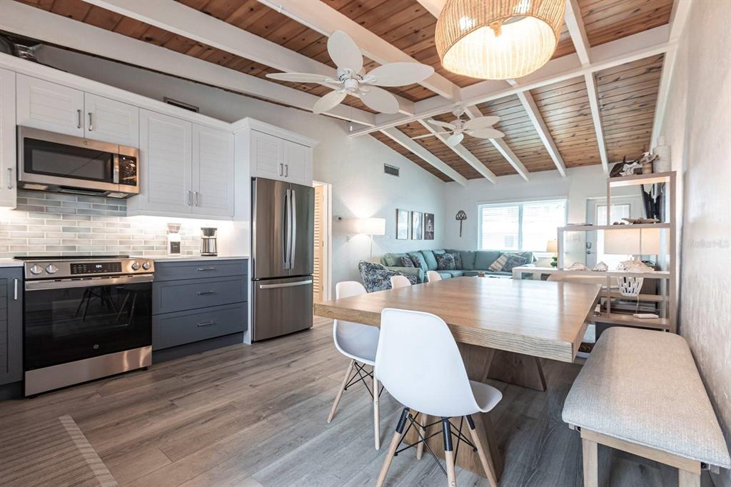 An open-concept kitchen and dining area features white cabinets, gray lower drawers, and wood ceilings — 6006 MIDNIGHT PASS ROAD UNIT 44, SARASOTA, FL