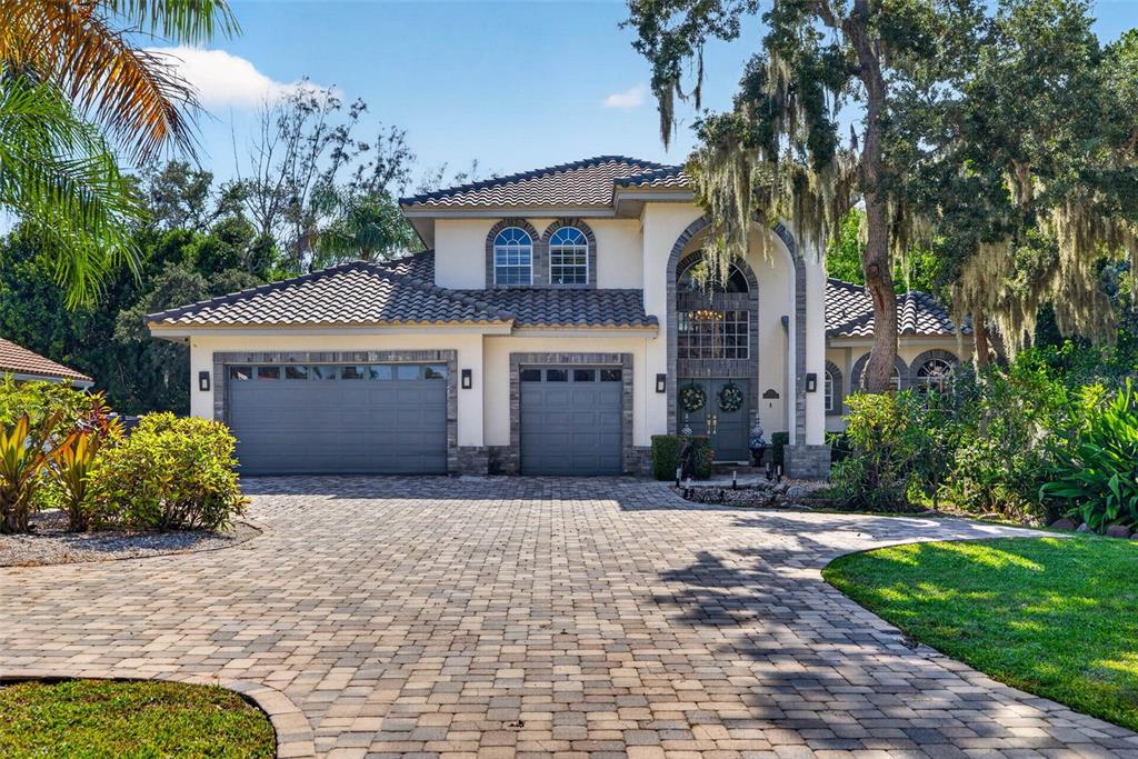 A two-story house with a paver driveway, three garage bays, and arched entryway features — 4660 LAUREL OAK LANE NE, ST PETERSBURG, FL