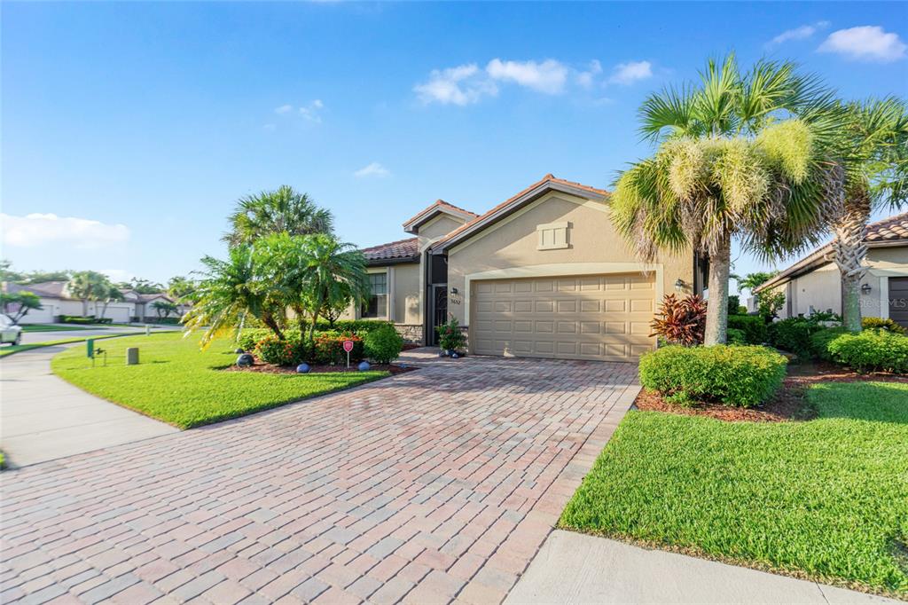 A single-story house with a tan stucco exterior, a two-car garage, and a paver driveway — 3652 TREASURE COVE CIRCLE, NAPLES, FL